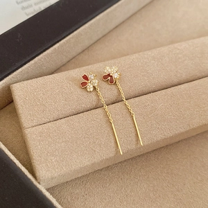 Detail of 18k gold plated four-leaf clover earrings with red enamel and zircon stones