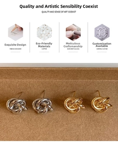 Close-up of gold and silver twisted knot copper earrings on a textured background