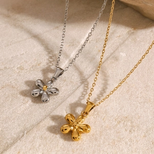 Elegant gold and silver flower pendant necklaces on a stone texture background