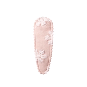 Detail of pink fabric hair clip with white 3D floral embroidery and textile texture