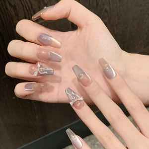 Detail of long trapezoid press-on nails with cat-eye gradient, bows, and pearls