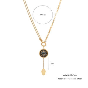 Macro view of gold Hamsa hand and Evil Eye pendants on stainless steel layered chain