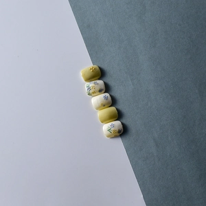 Detail of floral and blue butterfly relief patterns on yellow and white nail stickers