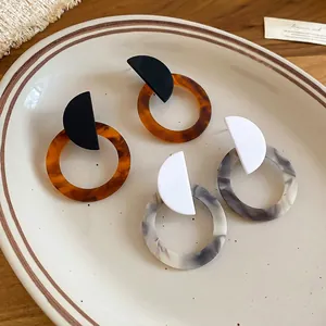 Retro resin tortoiseshell and marble round drop earrings set on a ceramic plate