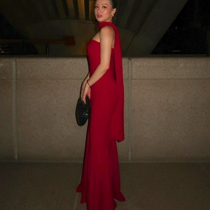 Side view of red one-shoulder slim fit evening gown with elegant flowing back shawl detail