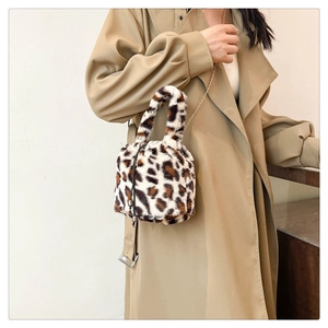 Detail of leopard print plush bucket bag with golden chain strap on stylish trench coat