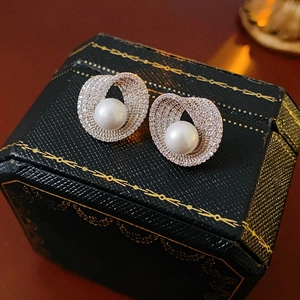 Détail macro de boucles d'oreilles perles blanches avec anneaux zircon sur boîte rétro
