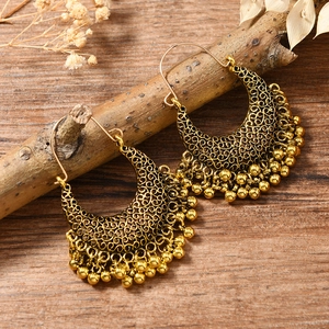 Gros plan de boucles d'oreilles bohèmes dorées en forme de croissant avec pampilles