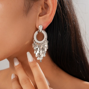 Boucles d'oreilles rondes argentées avec pompons pailletés sur modèle style bohème