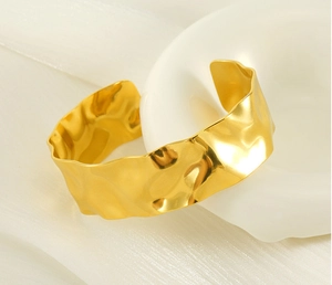 Macro shot of 18K gold plated cuff with hammer texture on luxury white fabric