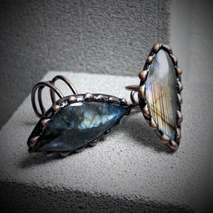Handmade labradordite rings in bronze finish with blue-green flashes on a gray stand