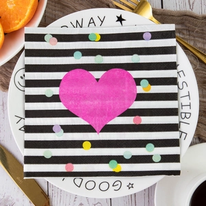 Macro view of square Valentine paper napkin with pink heart pattern on a dinner plate