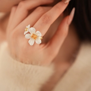 Detail of floral ring with white petals and golden band worn on a finger