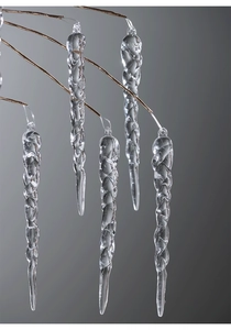 Detailed macro view of clear acrylic spiral icicle ornaments hanging on golden branches