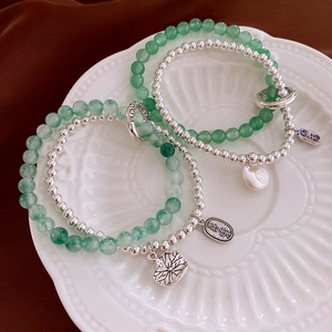 Detail view of green jade beads bracelet with silver Fu and Xi lucky pendants on ceramic