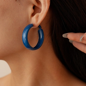 Gros plan d'un mannequin portant une boucle d'oreille créole géométrique bleu foncé brillante