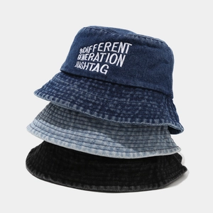 Detail of embroidered letters on stacked denim bucket hats in navy, blue and black