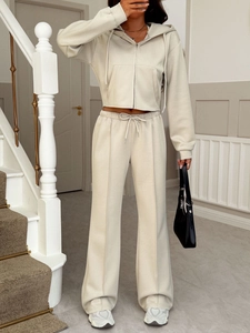 Détail d'un sweat à capuche beige zippé et pantalon large assorti avec couture centrale