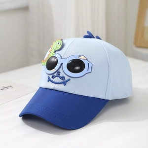 Détail de casquette enfant dinosaure avec lunettes 3D et sourire brodé bleu