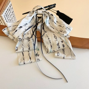 Detail of cream silk ribbon hair claw with black calligraphy patterns and long tassels