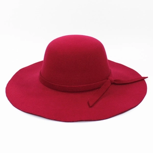 Detail view of the wide-brimmed red wool felt fedora hat with a matching ribbon bow