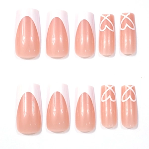 Detail of nude pink press-on nails with white French tips and hand-drawn heart patterns