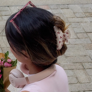 Detailed view of cream-colored acetate hair claw clip with cherry print and tiny rhinestones