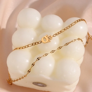 Double-layered gold Hamsa hand bracelet with Figaro chain links on a white display