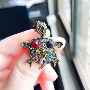 Vintage gold turtle brooch with colorful rhinestones on a natural light background