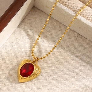 Macro view of vintage 18K gold plated heart pendant with red ruby on a bead chain
