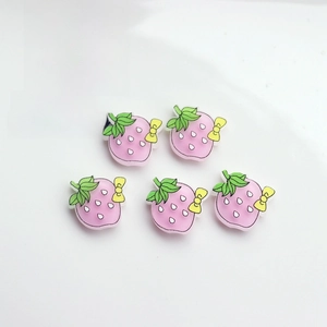 Close-up of pink strawberry DIY resin charms with green leaves and yellow bows for crafts