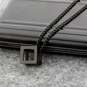Detailed close-up of a black cubic pendant on a metallic curb chain for men