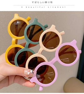 Detail of colorful round frame children sunglasses in yellow, green, cream, and purple