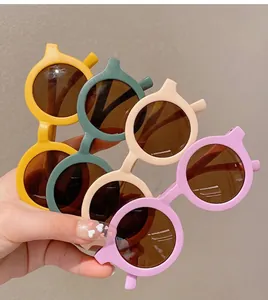 Dettaglio di occhiali da sole rotondi per bambini nei colori giallo, verde, crema e viola