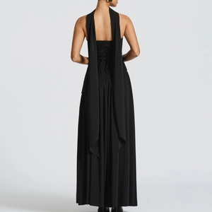 Close-up of elegant black backless dress featuring corset-style lacing and long flowing ribbons