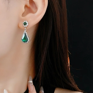 Detail of silver drop earring with green crystal and sparkling cubic zirconia halo