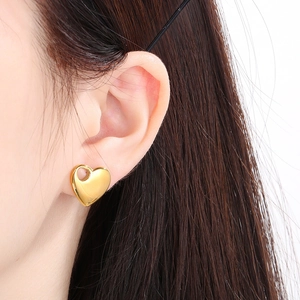 Close-up of gold plated 18K stainless steel heart-shaped stud earring on a model