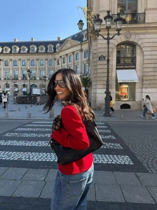 Close-up of a red bow-knot blazer paired with a black leather tote on a city street