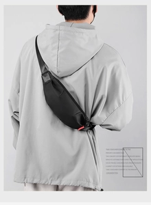 Rear view of a man wearing a minimalist black nylon crossbody chest bag over a grey hoodie