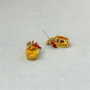 Macro shot of pineapple earrings with yellow crystals and tiny red enamel flower detail