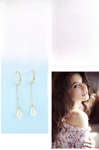 Detailed close-up of elegant gold chain earrings with white teardrop pearls and hook