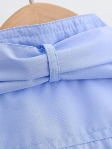 Detailed macro view of light blue shirt fabric showing plain weave texture and sewing lines