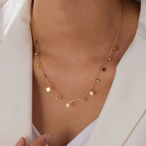 Collier élégant en acier doré avec pendentifs étoile et zircone porté par un modèle