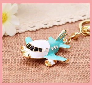 Detail of teal and white enamel airplane keychain with sparkling rhinestones and gold ring