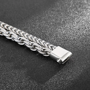 Macro di un bracciale in acciaio al titanio argento con catena intrecciata e chiusura