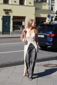 Detail of a beige sleeveless long knit cardigan with V-neck and stylish side slit design