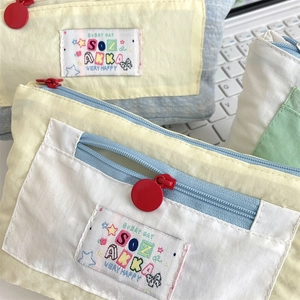Close-up of multicolor macaron canvas pencil case with red round zippers and woven label