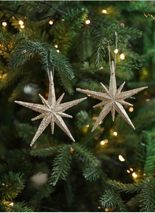 Close-up of sparkling gold star ornaments hanging on a lighted Christmas tree branch
