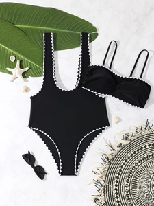 Close-up of black two-piece swimwear with white scalloped embroidery on marble background