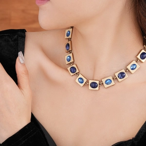 Nahaufnahme einer Vintage-Goldkette mit blauen quadratischen und ovalen Edelsteinen am Modell